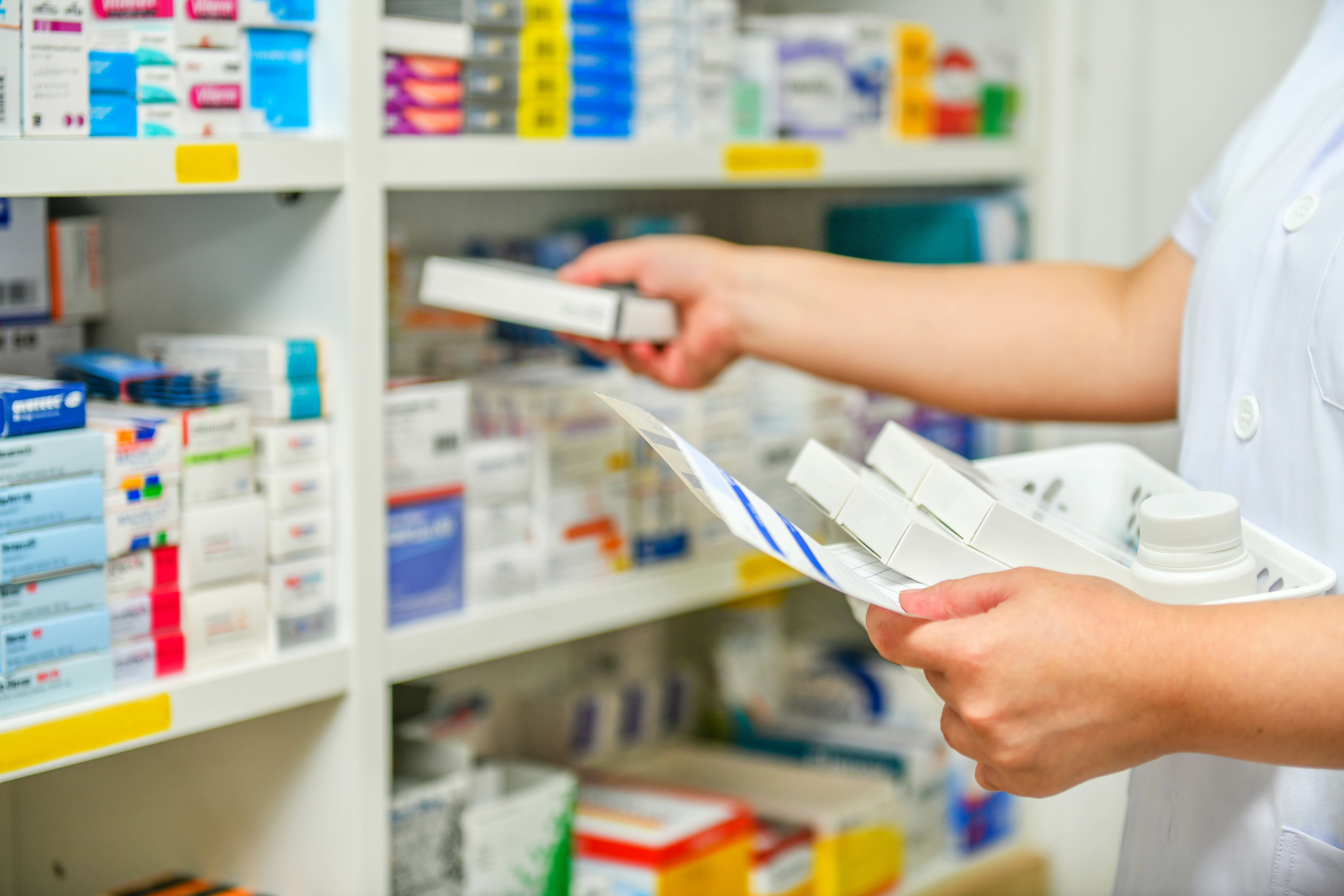 Pharmacist taking medication from a shelf.