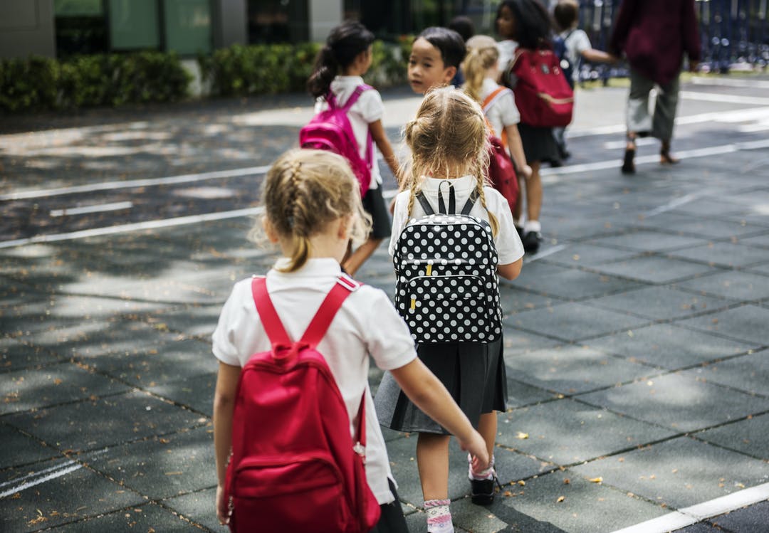 Children walking in a line with school bags