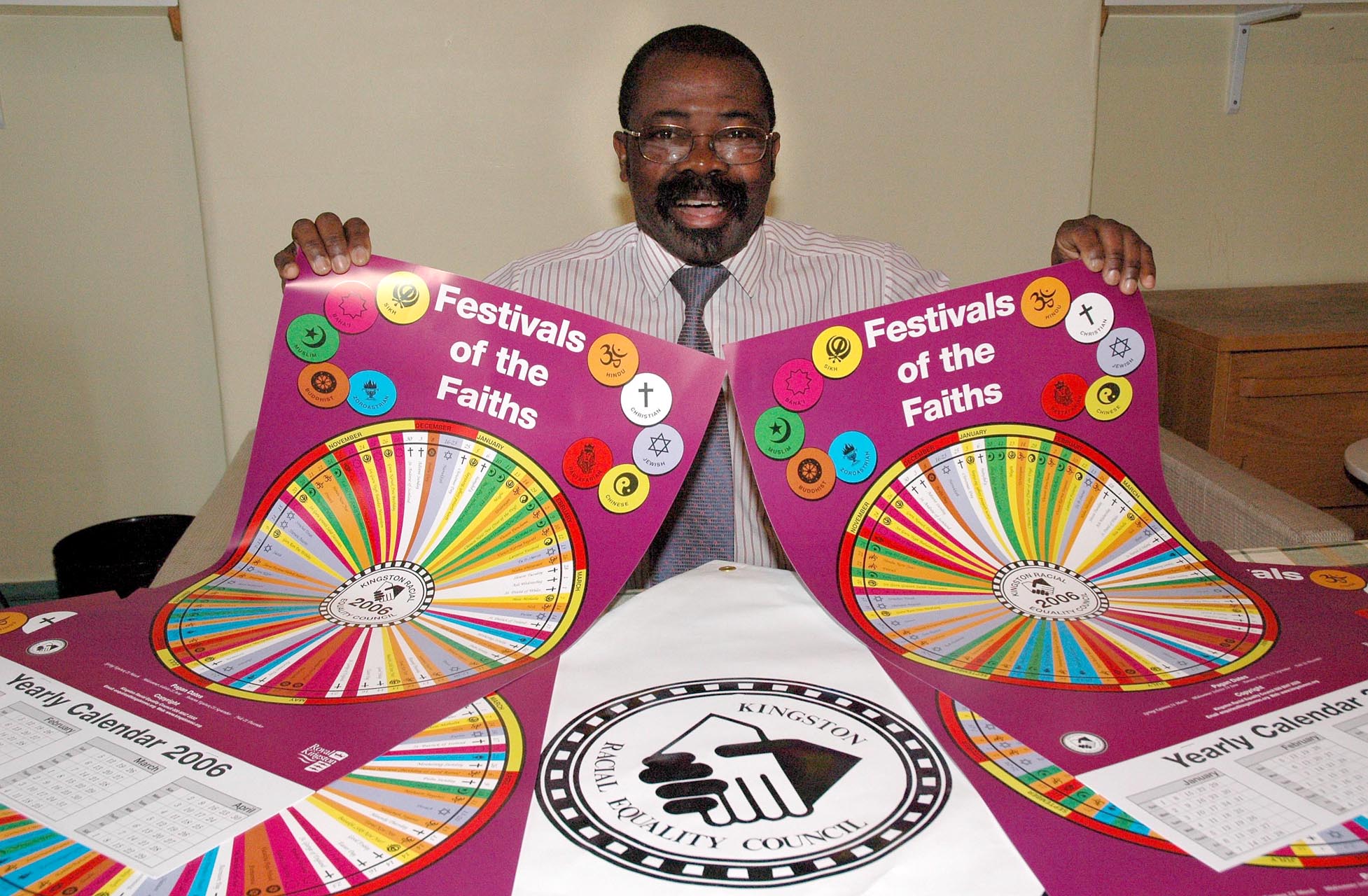 A picture of John Azah holding up a 'festival of the faiths 2006' poster