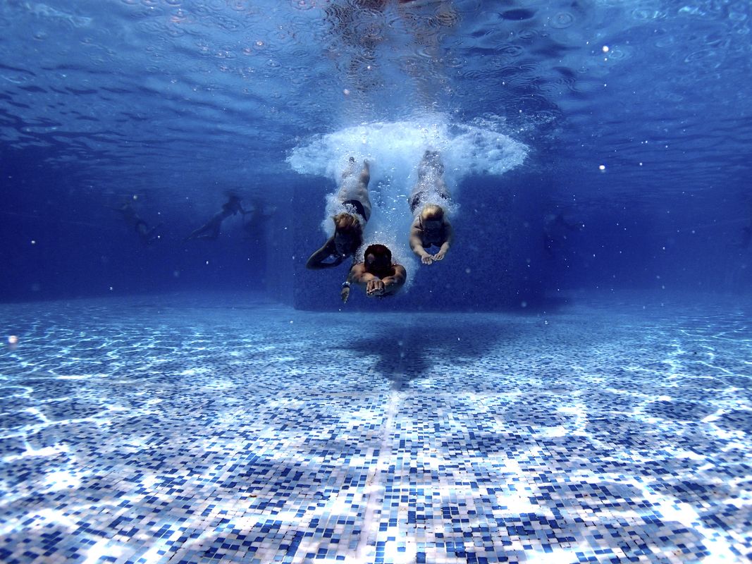 Image of three people jumping into a swimming pool