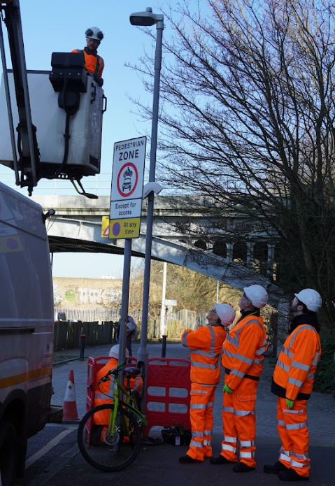 Caption: Councillors Nicola Nardelli, Ian Manders and Andreas Kirsch (Leader of Kingston Council) inspect the replacement of an old streetlamp on Thameside Road in Kingston.