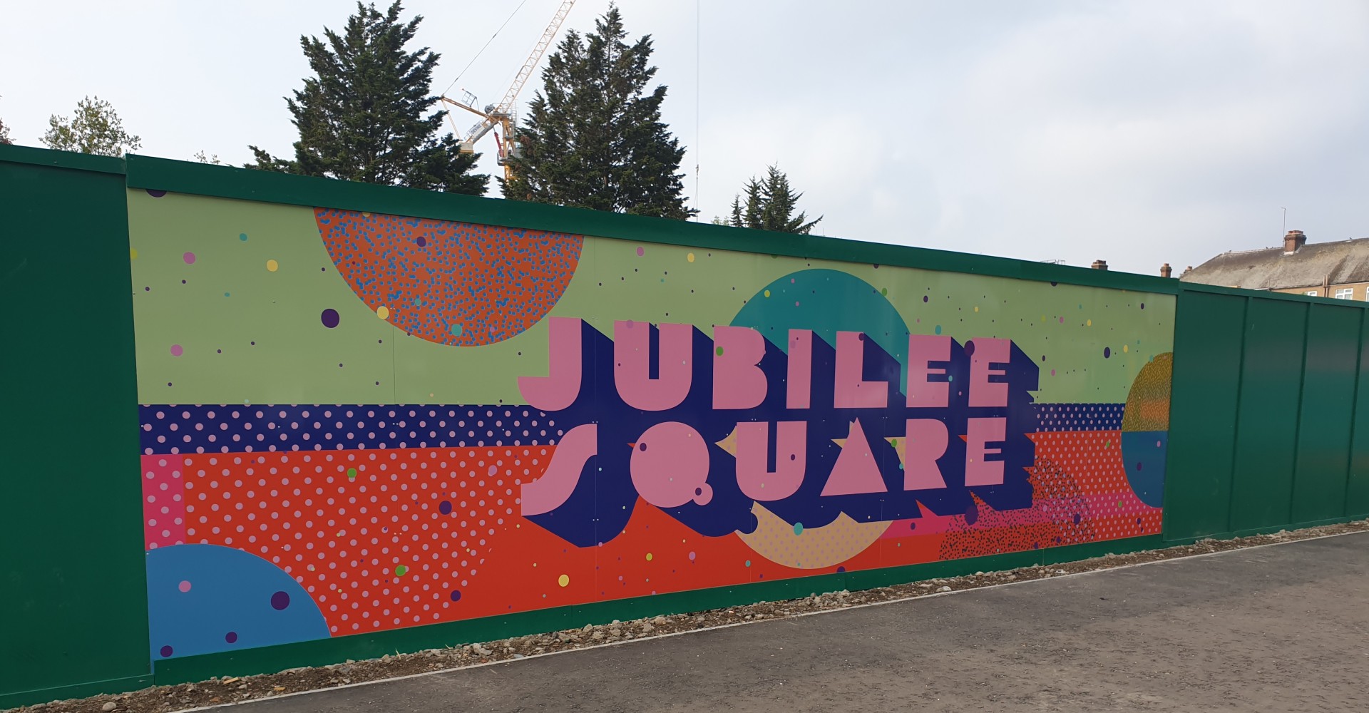 One of Jubilee Square hoardings, colourful piece of street art with the square's name in pink typography.