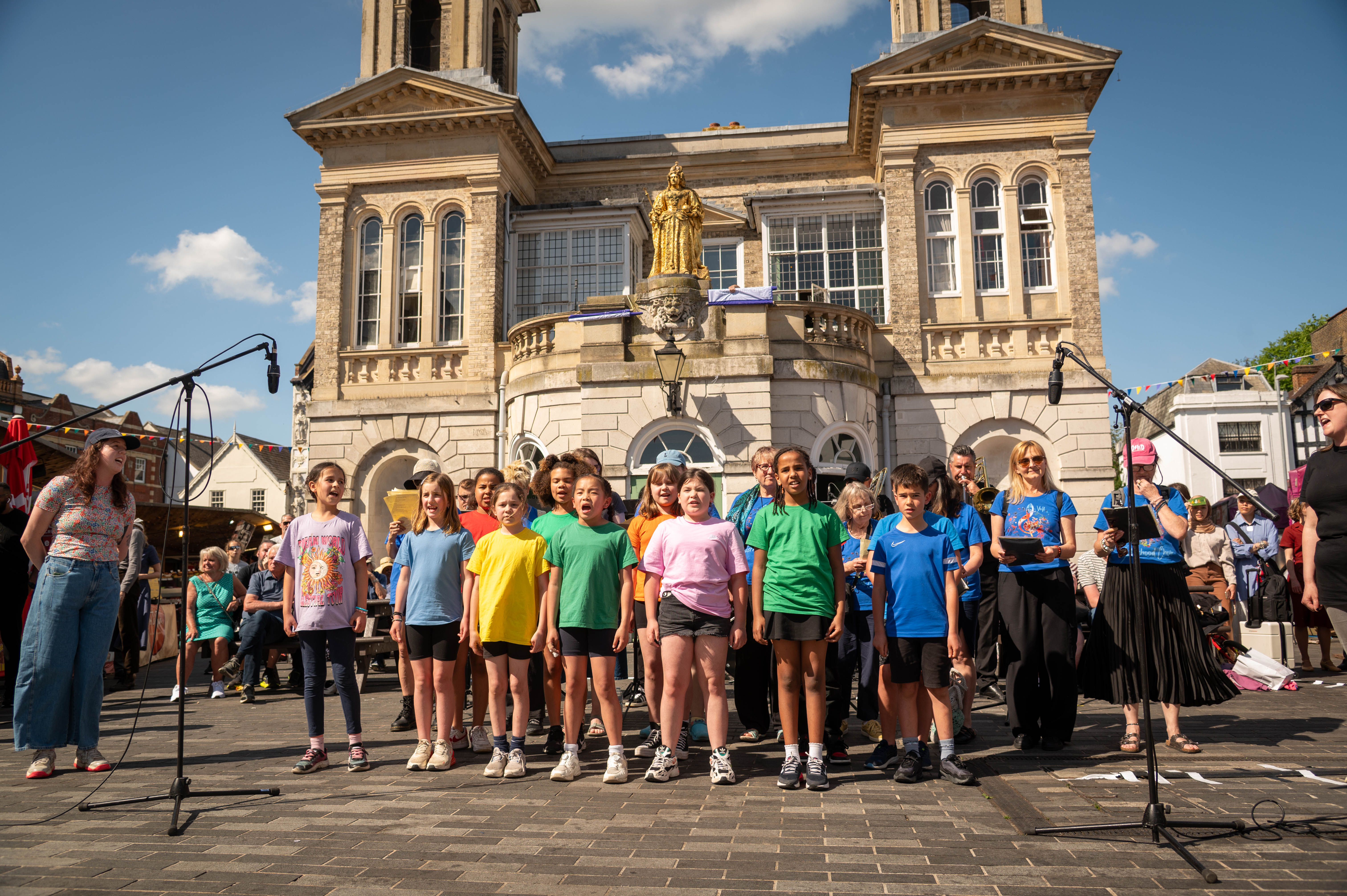 a choir of children singing in front of the ancient market house in Kingston
