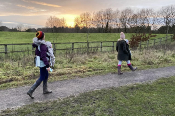 Two people walking in the countryside on a road