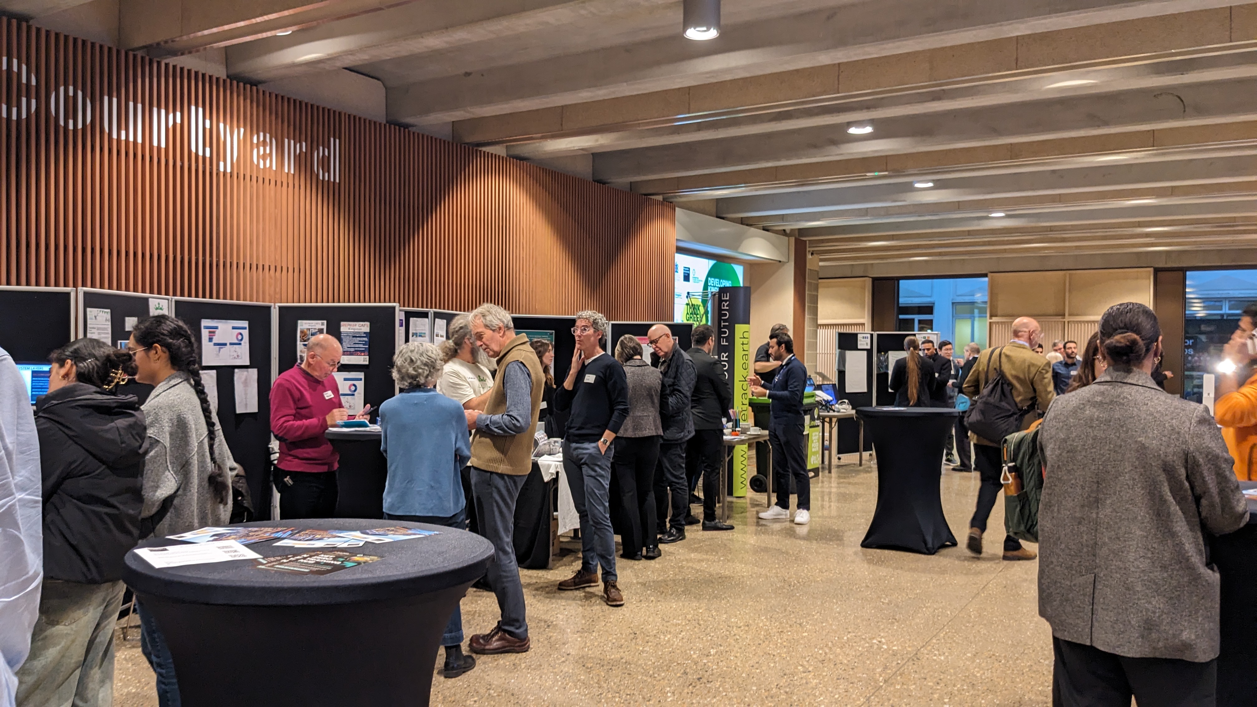 A group of people mingle in a large hall at Kingston University