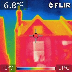 A thermal image of a house. Warm sports of the walls are a bright red while the surrounding sky are a cool blue.