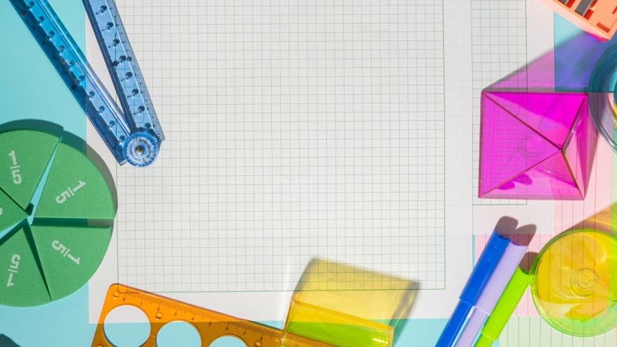 A close up, taken from above, of a sheet of graph paper with design tools scattered around it