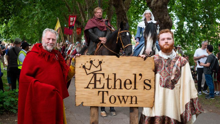 Saxon reenactors in Canbuy Gardens stand next to a wooden sign saying Athel's Town