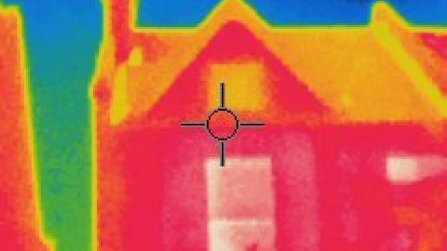 A thermal image of a house. Warm sports of the walls are a bright red while the surrounding sky are a cool blue.